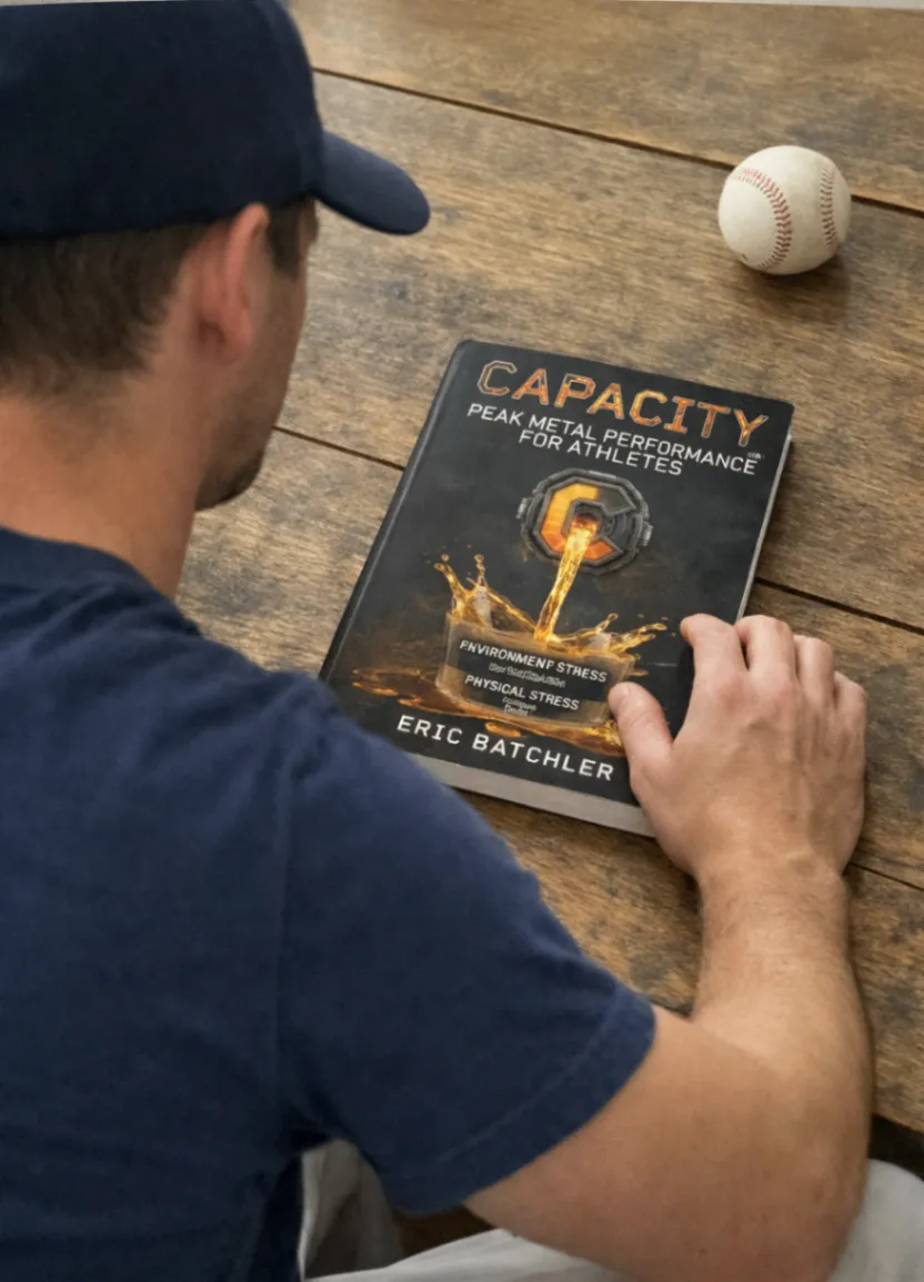Athlete reading the Capacity: Peak Mental Performance for Athletes book beside a baseball